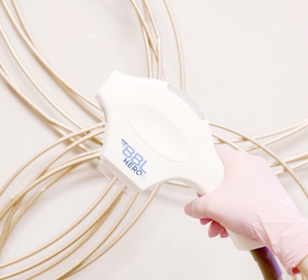 A professional wearing gloves operates a handheld device used for rosacea treatment in Oklahoma City